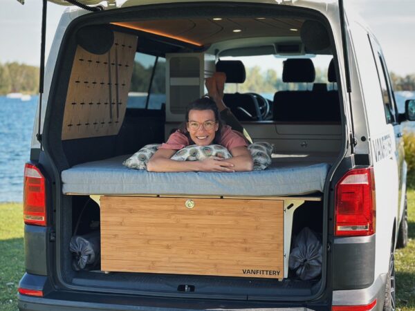 Una persona descansa relajada sobre un sistema de descanso en el maletero de una furgoneta.